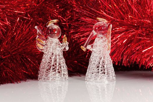 Two decorative glass angel and Christmas tree tinsel on white with reflections