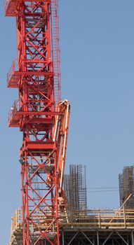 Red Construction Crane on Rooftop of Skyscraper set against a blue sky background.