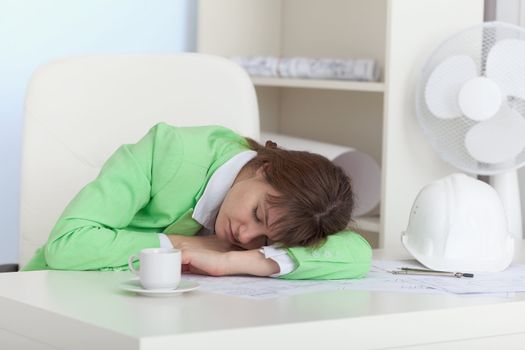 The girl sleeps on a table at office in working hours