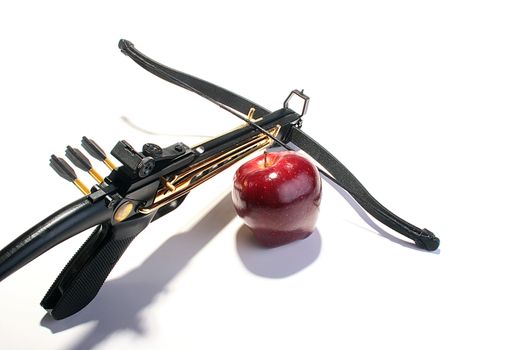 Crossbow with arrows and a red apple.