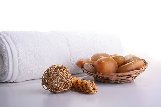 Subjects for SPA: a towel, stones in a basket and a decorative wattled sphere from wood.