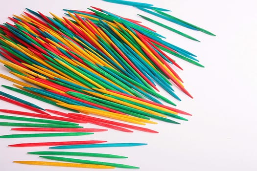 Toothpicks sharp from two parties, different colours are poured out on a white table.