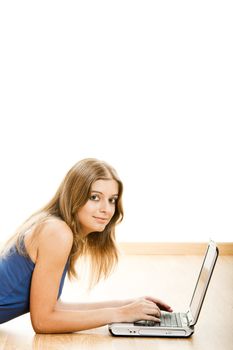 Beautiful young woman lying on floor and working on a laptop