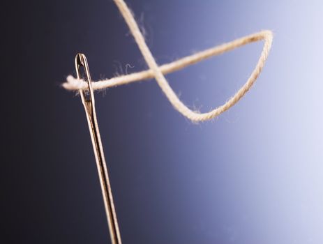 White thread going through needle eye, closeup