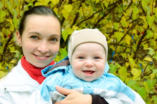 Happy mother and baby boy over autumn background
