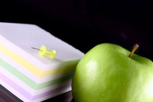 Green apple with the block for records and a pin removed close up on the blacked out glass