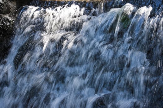 Water splashing down from waterfall on summer afternoon