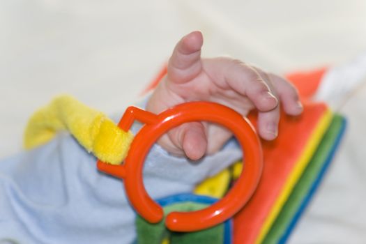 Hand from five months old baby playing with colorful book made from fabric - horizontal