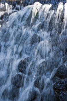 Water splashing down from waterfall on summer afternoon