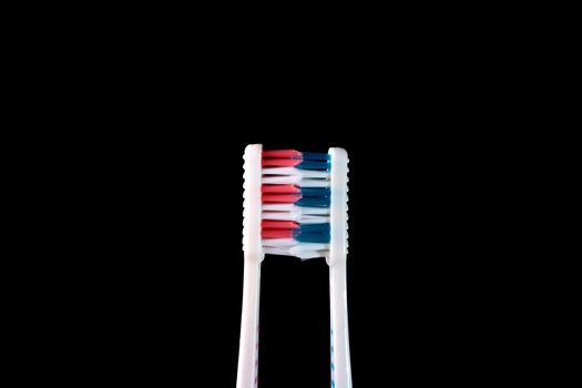 Two new tooth brushes on a black background.