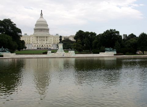 The west side of the United States Capitol building reflected in a pool.
