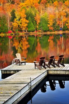 Wooden dock with chairs on calm fall lake