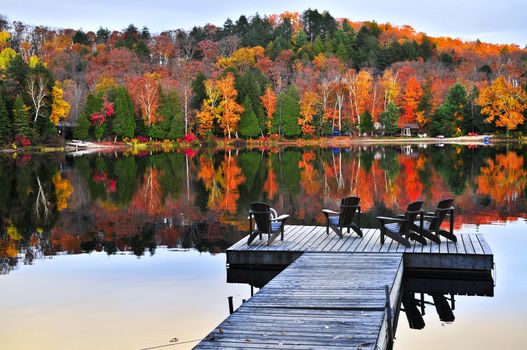 Wooden dock with chairs on calm fall lake