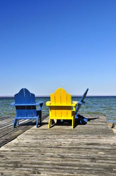 Painted wooden chairs on dock at a lake