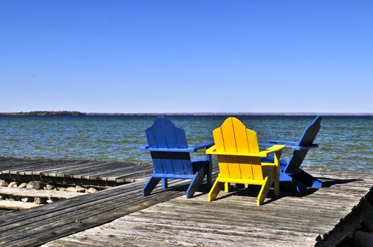 Painted wooden chairs on dock at a lake