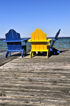 Painted wooden chairs on dock at a lake