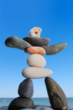 Figurine of sea pebbles on the against the blue sky