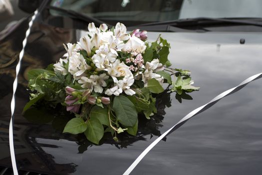 bouquet of flowers on the hood of wedding car
����