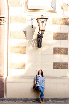 Girl standing near wall under lamp
