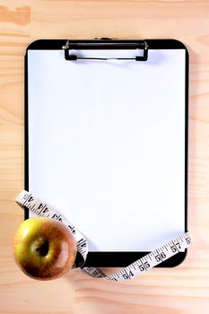 The apple, tape measure and blank clipboard for those who takes a great interest in diets.