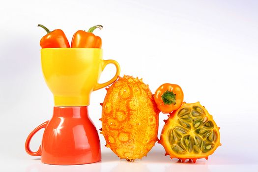 Two cups with vegetables a hot pepper and Kiwanos, one of Kiwanos is cut. Exotic fruit Kiwanos, is used for preparation of salads and for an ornament of dishes.