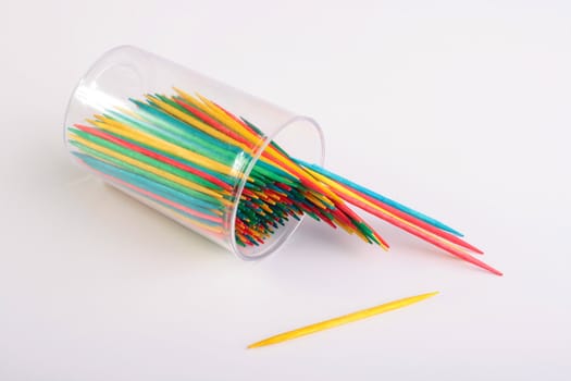 Toothpicks sharp from two parties, different colours are poured out on a white tab