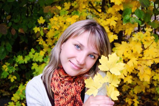 Girl with yellow autumn leaves over trees
