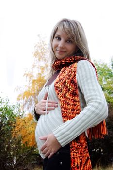 Smilng pregnant woman in autumn park with scarf