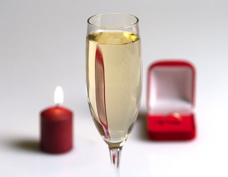 Champagne glass, candle and box with a gift.