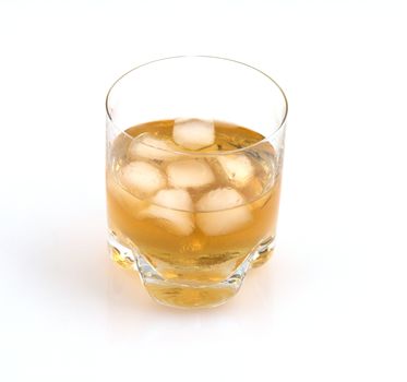 Close up of a glass of whisky with ice cubes on a white glossy background.