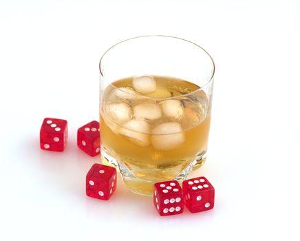 Glass of whisky with ice and red playing bones.