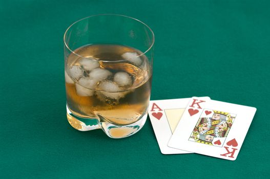 As the king of hearts and a glass of whisky with ice on green cloth.