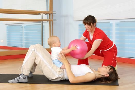 Mother and the child are engaged with the instructor in a sports hall
