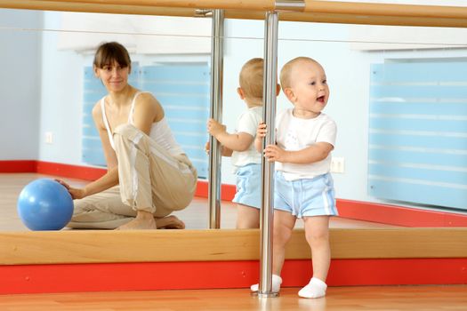 Mother and the child are engaged with the instructor in a sports hall
