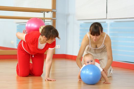 Mother and the child are engaged with the instructor in a sports hall
