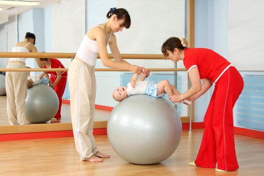 Mother and the child are engaged with the instructor in a sports hall
