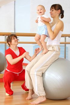 Mother and the child are engaged with the instructor in a sports hall
