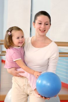 Mother and the child are engaged with the instructor in a sports hall
