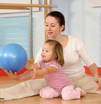 Mother and the child are engaged with the instructor in a sports hall
