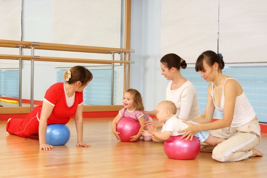 Mother and the child are engaged with the instructor in a sports hall
