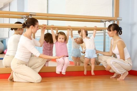 Mother and the child are engaged with the instructor in a sports hall
