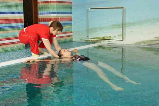 The instructor conducts lesson with the pregnant woman in pool