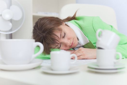 The beautiful woman sleeps on a workplace with coffee cups