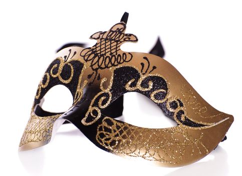 A fancy venetian mask shot against a white background with part of it's reflection in front