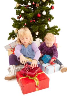 Christmas - Cute young girls opening their presents under a christmas tree