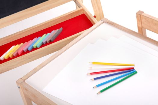 details of blackboard with chalks and desk with pencils in kindergarten