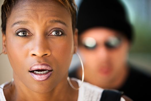 Woman being stalked by criminal in sunglasses and ski hat