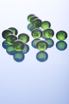 green capsules scattered on blue background, close up