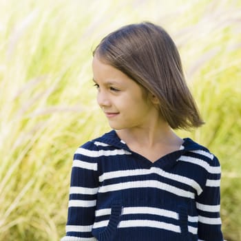 Portrait of A Smiling Young Girl In Striped Sweater Standing in Grass