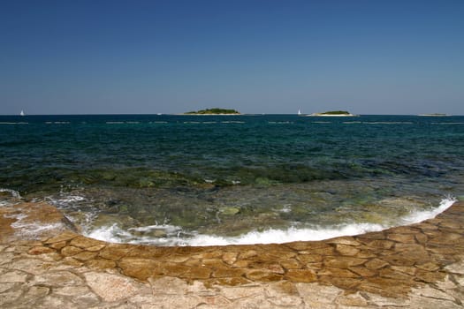 Wave bashing on sore with islands in the background